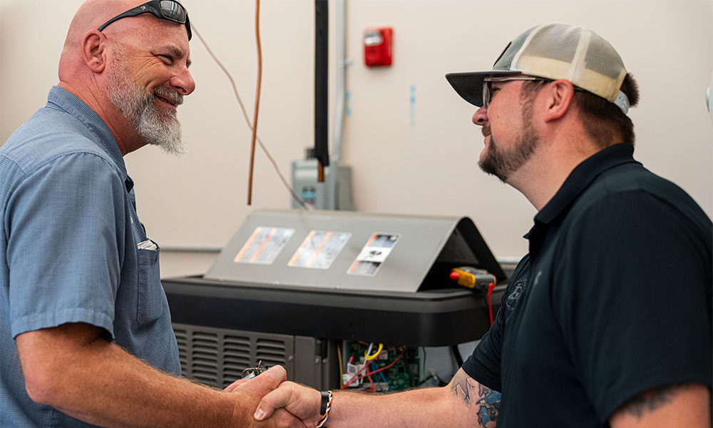 shaking hands in front of hvac unit