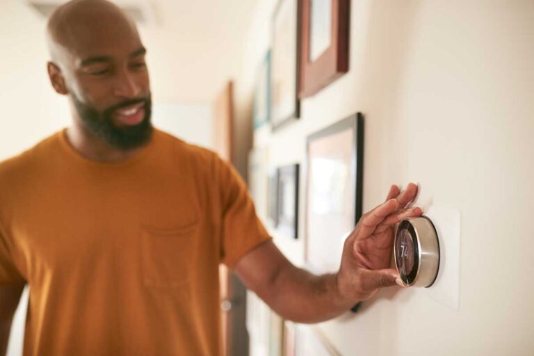 man adjusting thermostat
